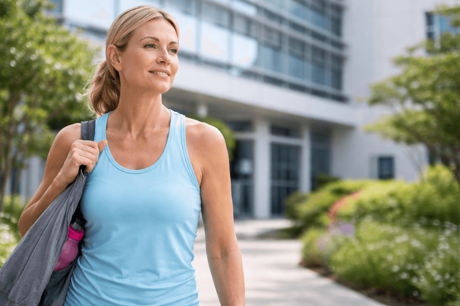 Fair skinned woman walking outside modern hospital in athletic wear representing metabolic health and lifestyle support during breast cancer treatment