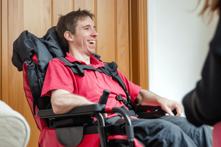 ALS motor neuron disease treatment showing a patient in a powered wheelchair receiving supportive home care