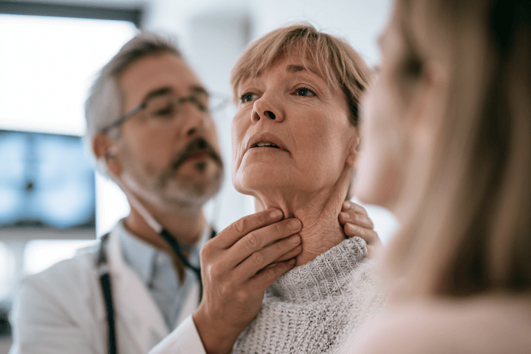 An oncology specialist examining a patient with anaplastic thyroid cancer and visible lower-neck swelling in a modern hospital.