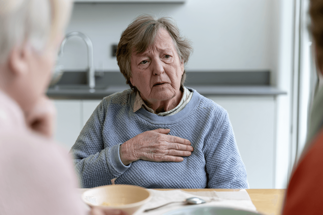 Stage 4 Esophageal Cancer: Symptoms, Survival And What To Expect 3 Patient pausing a meal with a hand over the upper chest while a companion sits nearby.