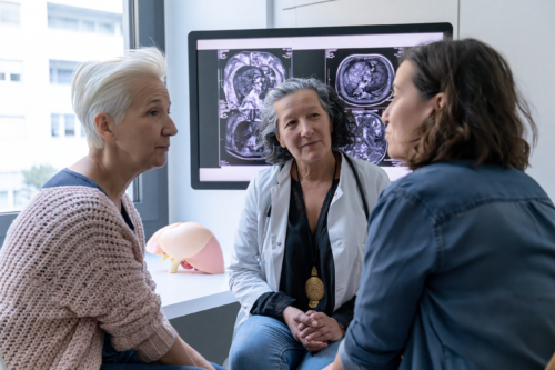 Hepatologist reviewing liver MRI scans with a patient and caregiver during hepatocellular carcinoma treatment planning.
