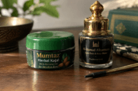 Home 8 Illustrative kajal and kohl containers with a gold-handled applicator on a wooden table.